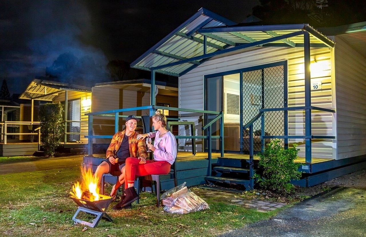 Couple By Fire Outside Cabin